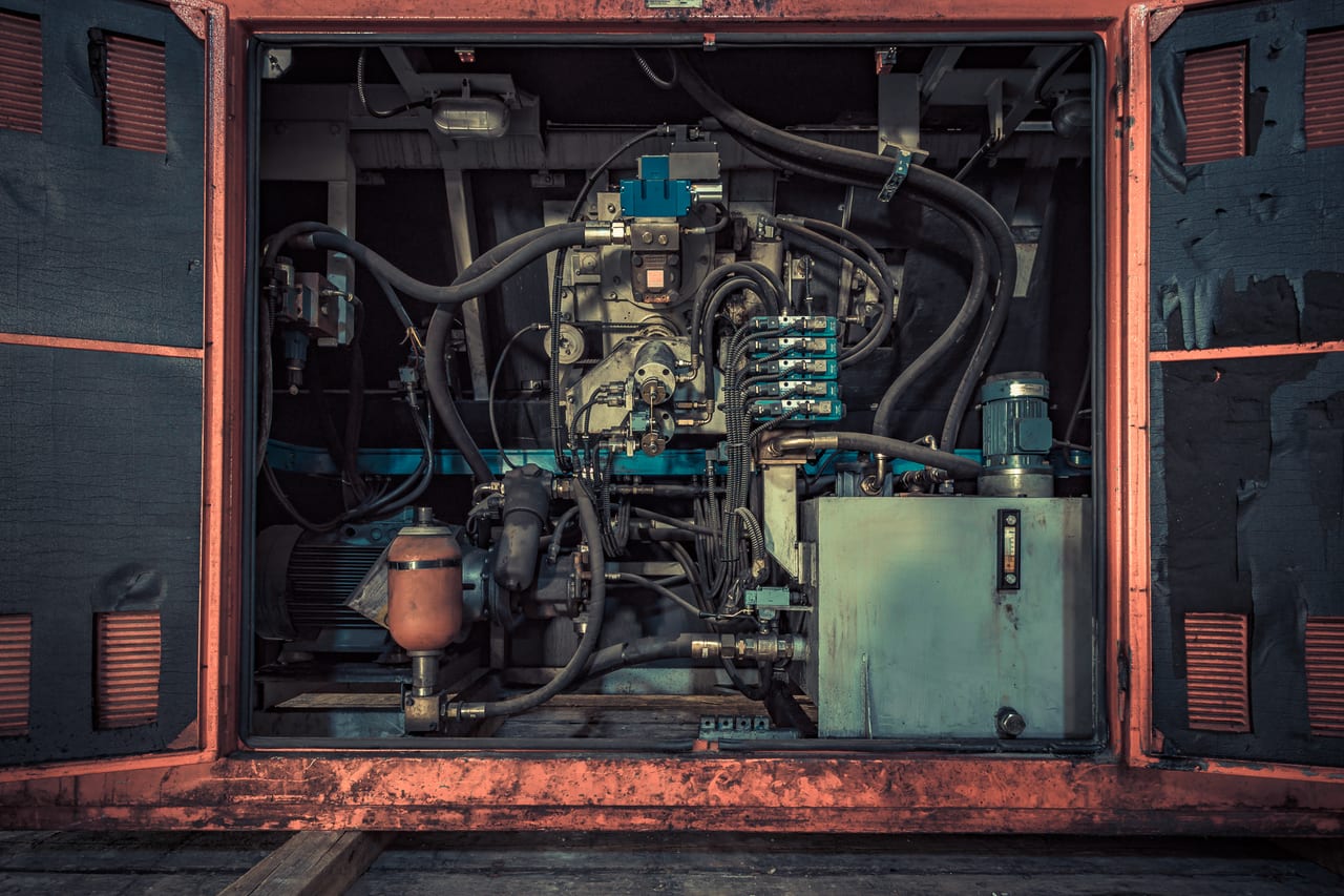 Ein verfallener Innenraum einer Industriemaschine zeigt stark korrodierte Systeme mit Hydraulikleitungen und Ventilen.