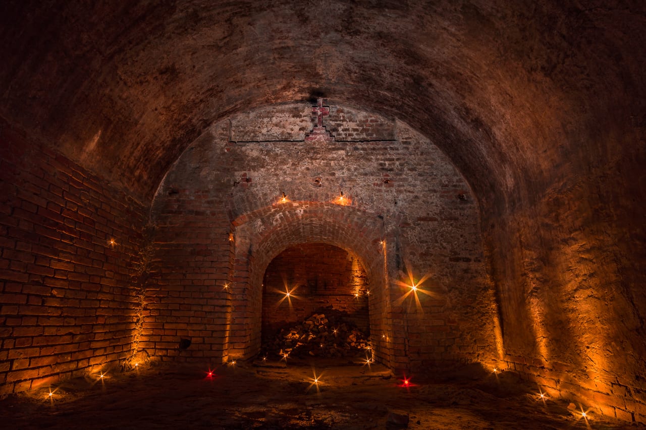 Eine verlassene, gewölbte Tunnelstruktur aus Backsteinen mit sichtbaren Rissen und Erosion.