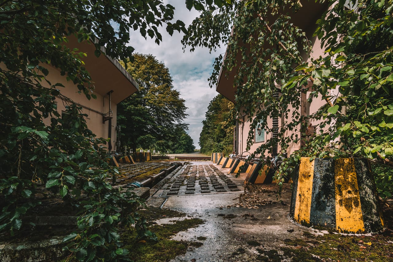 Eine verlassene Panzer Waschanlage auf einem alten Militärstützpunkt, die von dichtem Grün und Blättern überwuchert wird.